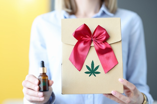 Woman holds box and bottle of marijuana in her hand