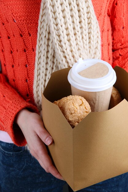 Woman holds box with coffee and cookies closeup