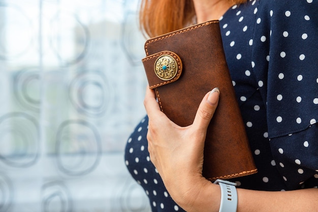 女性は手に茶色の天然皮革の財布を持っている