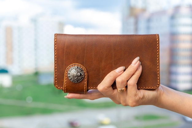 Woman holds a brown natural leather wallet in her hand