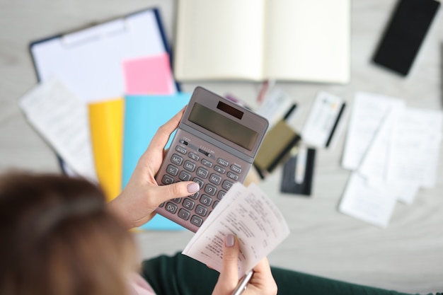 Woman holds calculator and paid check cost control concept