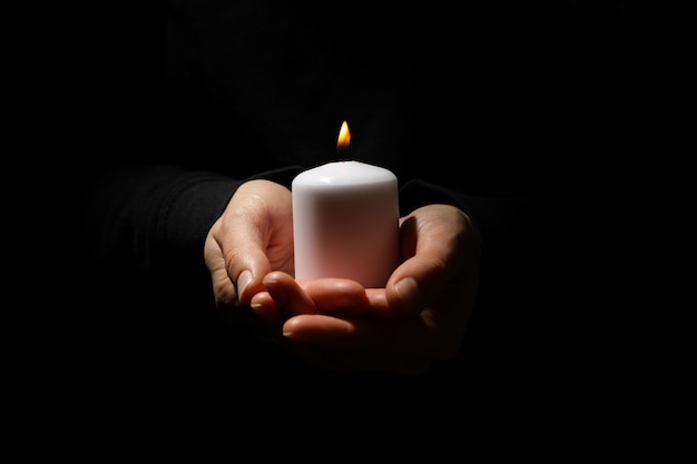 Woman holds candle on black