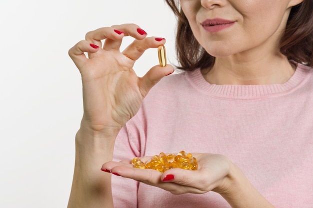 Woman holds capsule with vitamin E, fish oil