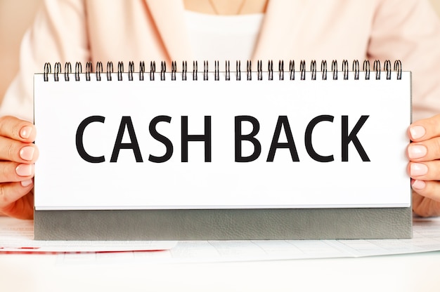 The woman holds a cardboard with hands with the text CASH BACK. Text writing black letters