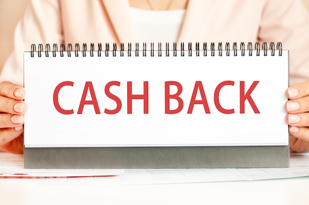 女性はテキストCASHBACKで手で段ボールを持っています