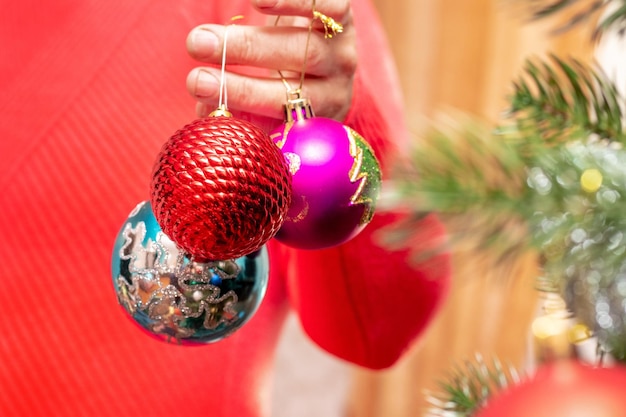 クリスマスの飾りのおもちゃとクリスマス ツリーを手に持つ女性 クリスマス ツリーを飾る年配の女性