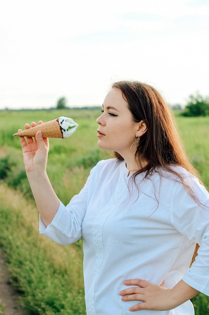 한 여성이 손에 아이스 캔디가 든 콘을 들고 있습니다. 여름에 시원한 디저트.