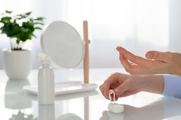 A woman holds a contact lens on her finger to put it on her eyes.