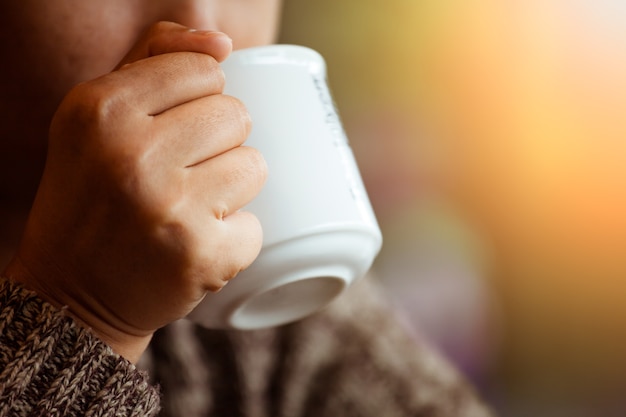 女性は雨の日にカフェでコーヒーのカップを保持していますヴィンテージの色調