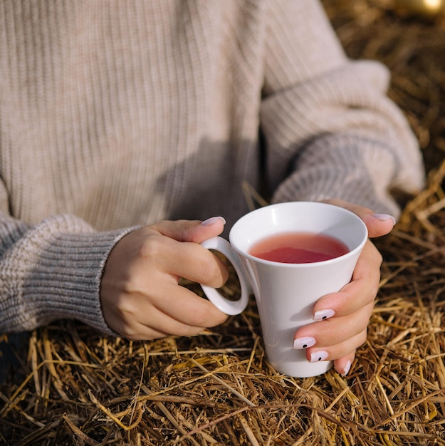 A woman holds a cup of tea close up