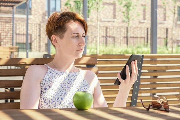 Woman holds an ebook device and a reusable coffee cup in her hands