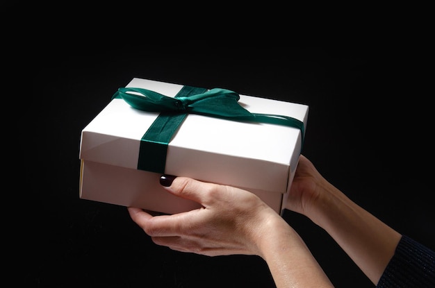 A woman holds a gift in her hands on a black background