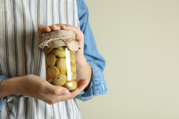 Woman holds glass jar of marinated mushrooms