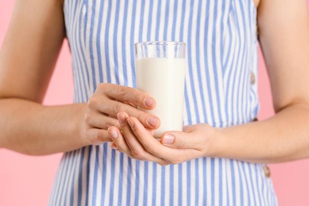 Photo a woman holds a glass of milk in her hands, close-up