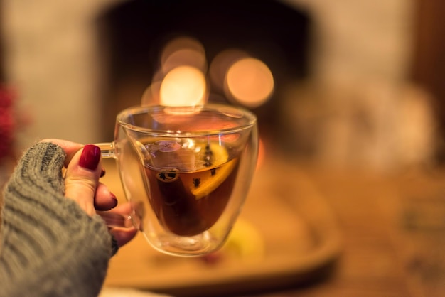 暖炉の前でお茶を飲む女性。