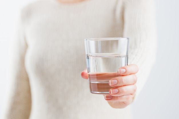 A woman holds a glass of water in her hands. Health care concept.