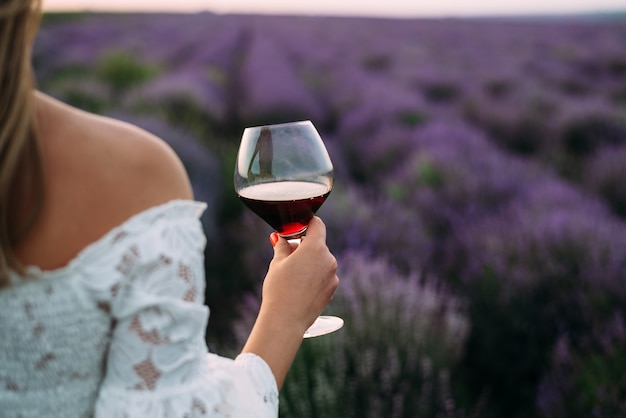 La donna tiene un bicchiere di vino nel campo di lavanda