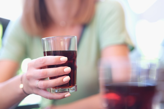 Woman holds glass with brown liquid