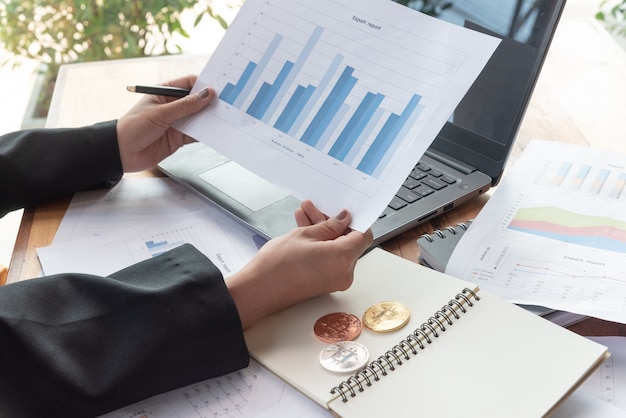 Photo woman holds graph paper with bitcoin beside