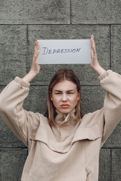 Photo woman holds in hand sheet of paper with word depression