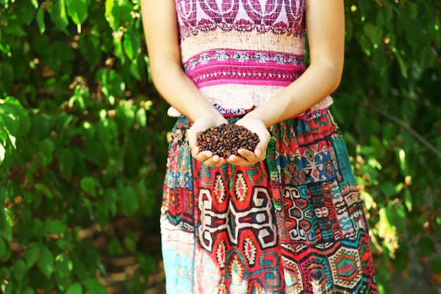 Woman holds in hands roasted coffee beans close up