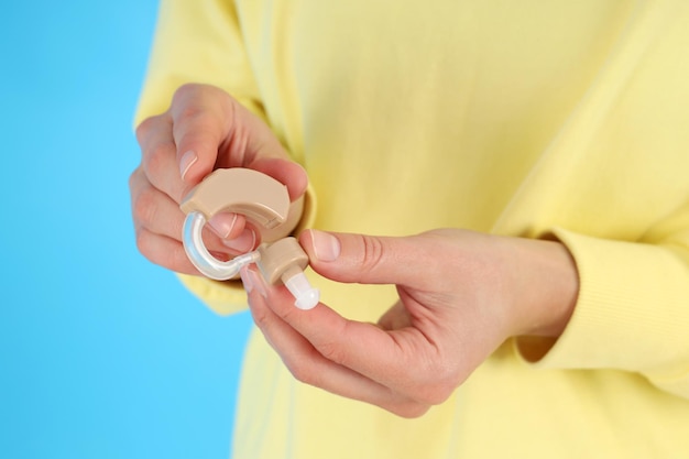 Woman holds hearing aid on blue background