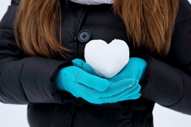 Женщина держит сердце из снега. Концепция Дня святого Валентина
