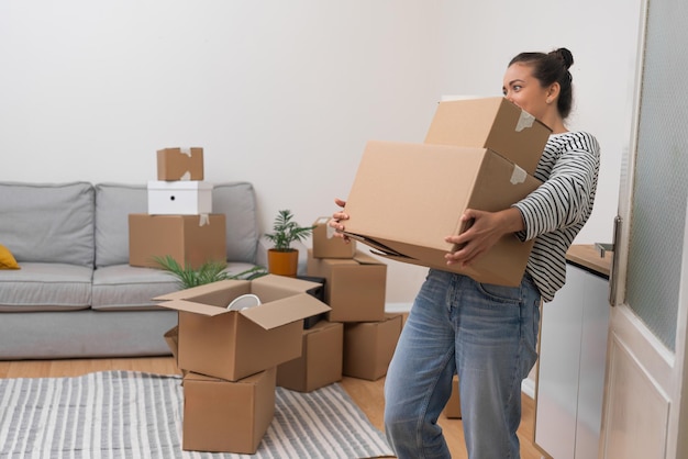 woman holds heavy boxes with personal items in light premise