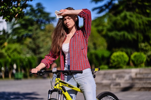 写真 女性は彼女の額を保持し、夏の公園で暑い天気に苦しんでいます。