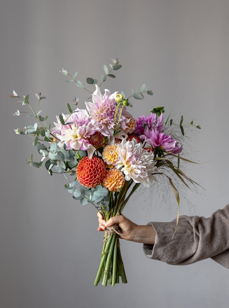 A woman holds in her hand a festive flower arrangement with bright chrysanthemum flowers, a festive bouquet.