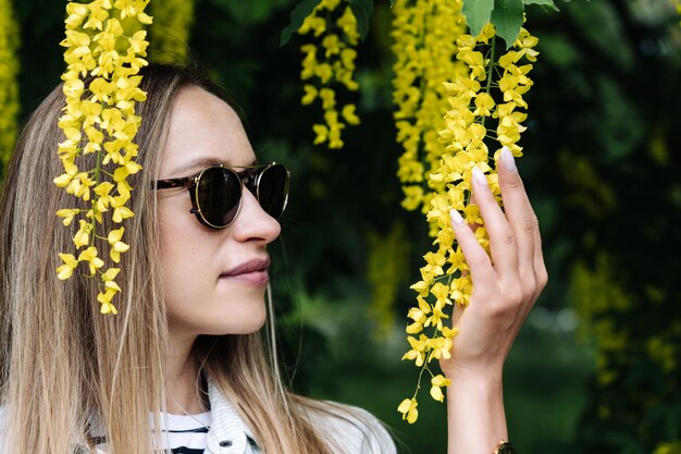 Photo a woman holds in her hand the inflorescence of laburnum anagyroides