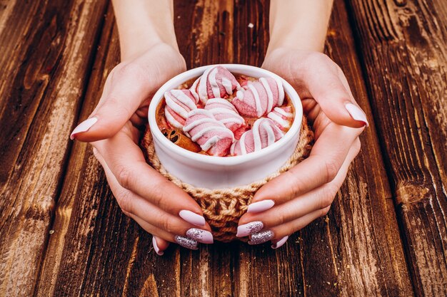 La donna tiene nelle sue mani tazza con cioccolate calde e marshmallow