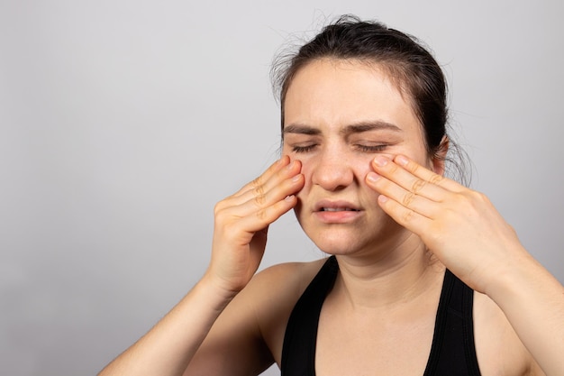 The woman holds her hands on the face pain in sinuses