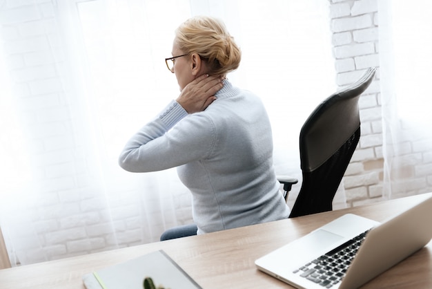 Photo woman holds her hands to her neck.