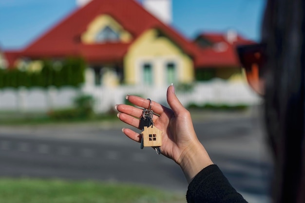 Una donna tiene in mano le chiavi della casa sullo sfondo di edifici residenziali concetto per l'acquisto e l'affitto di appartamenti