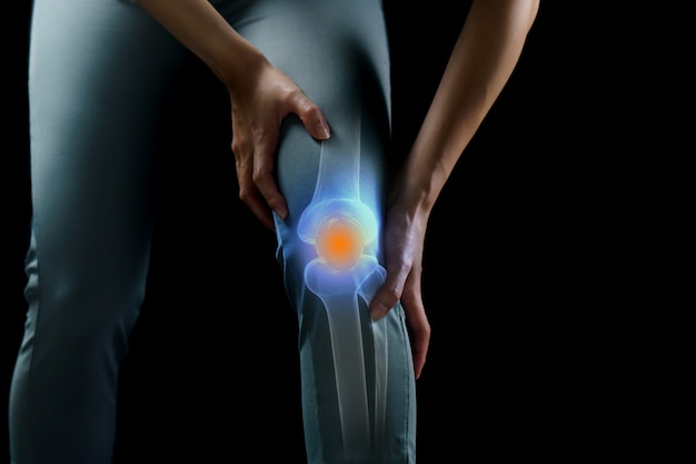 Фото Женщина держит ее руки к колену, боль в колене выдвинута на первый план в сини, медицине, концепции массажа.