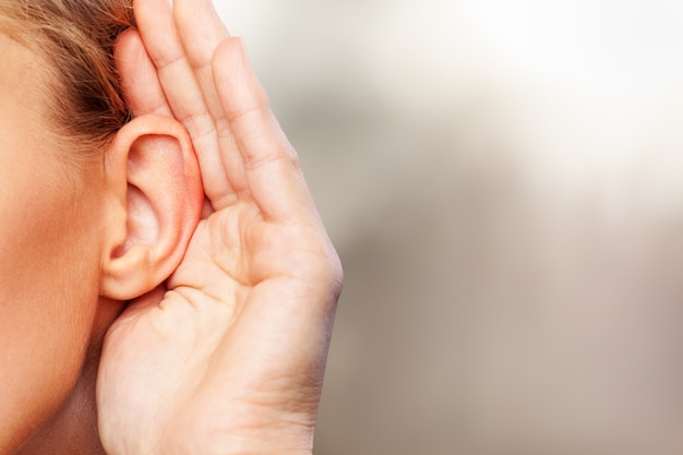 A woman holds his hand near his ear and listening to something