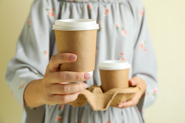 女性は紙のコーヒーカップでホルダーを保持します