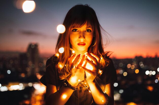 a woman holds a light in her hands in front of a night sky