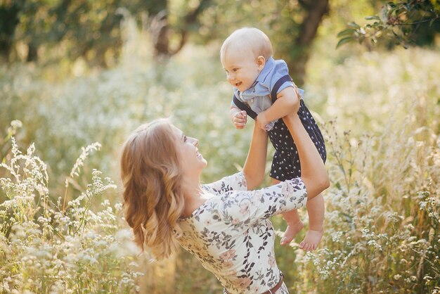 Woman holds little son in her arms in summer park