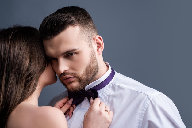 Woman holds mans bowtie, bow tie. Sexy couple in love. Sensual lovers undressed. Girlfriend and boyfriend sensual hugging. Boy girl romantic embracing. Tender hug. Naked passion body.