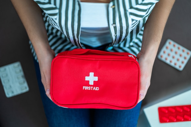 Woman holds a medical kit with medicine at home. First aid for pain and illness