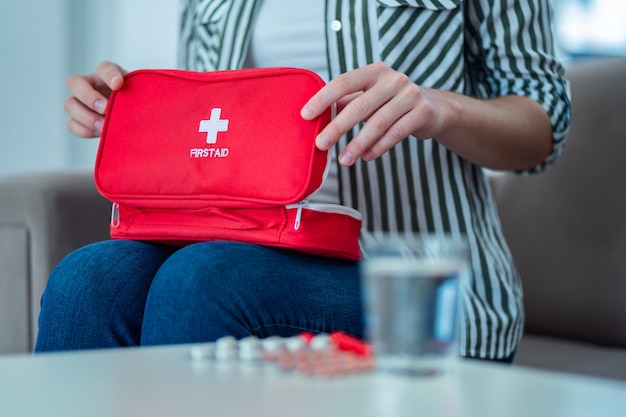 Woman holds a medical kit with medicine at home. First aid for pain and illness