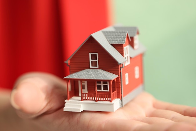 A woman holds a model of a red house a closeup buying and housing insurance rent real estate