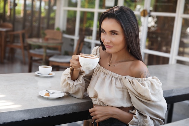 La donna tiene una tazza con caffè e sorridente.