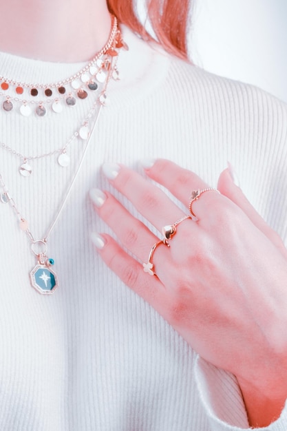 A woman holds a necklace with a blue stone on it.