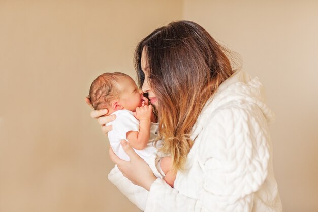 A woman holds a newborn baby touching his nose with her nose.
high quality photo