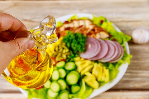 Woman holds olive oil for vegetable salad