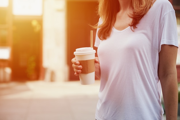 Woman holds paper coffee cup at city street