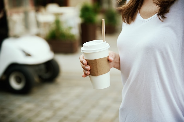 Woman holds paper coffee cup at city street